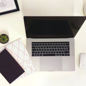 Minimalist workspace featuring a laptop, notepads, and a mouse in Budapest.