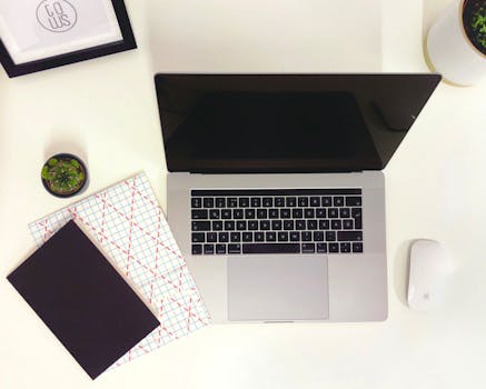 Minimalist workspace featuring a laptop, notepads, and a mouse in Budapest.