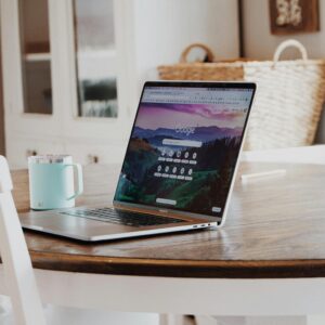 A sleek laptop on a wooden table with a mug, exemplifying a modern home workspace.